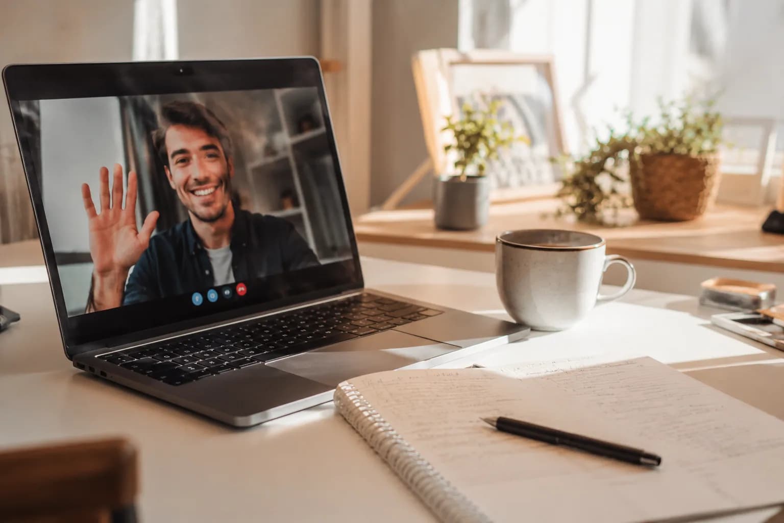 Rozmowa wideo z klientem na ekranie laptopa, notatki na biurku obok
